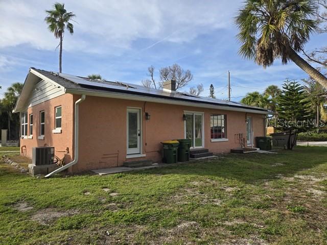 The exterior of a peach-colored house features solar panels on the roof and a yard — 3615 HIGEL AVENUE, SARASOTA, FL