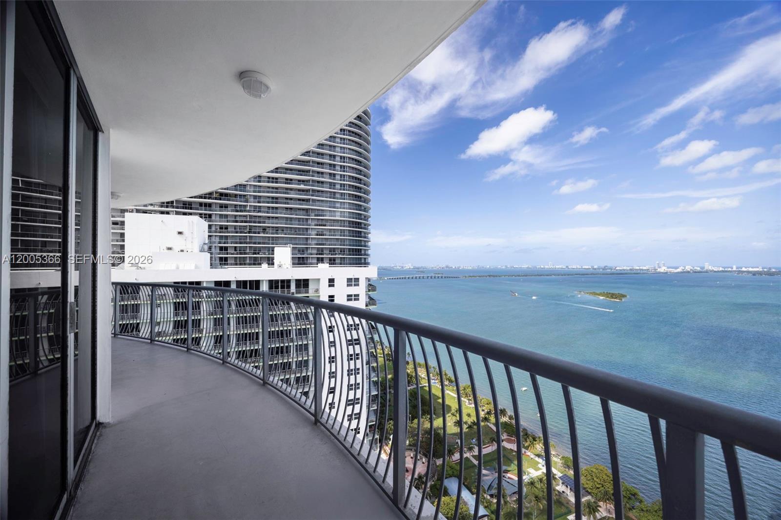 A curved balcony overlooks a bay with a park and a neighboring high-rise building — 1750 N Bayshore Dr # 3801, Miami FL 33132, MIAMI, FL