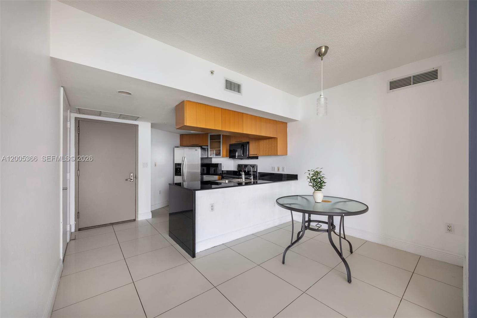A kitchen with wood cabinets and black countertops sits next to a glass dining table — 1750 N Bayshore Dr # 3801, Miami FL 33132, MIAMI, FL