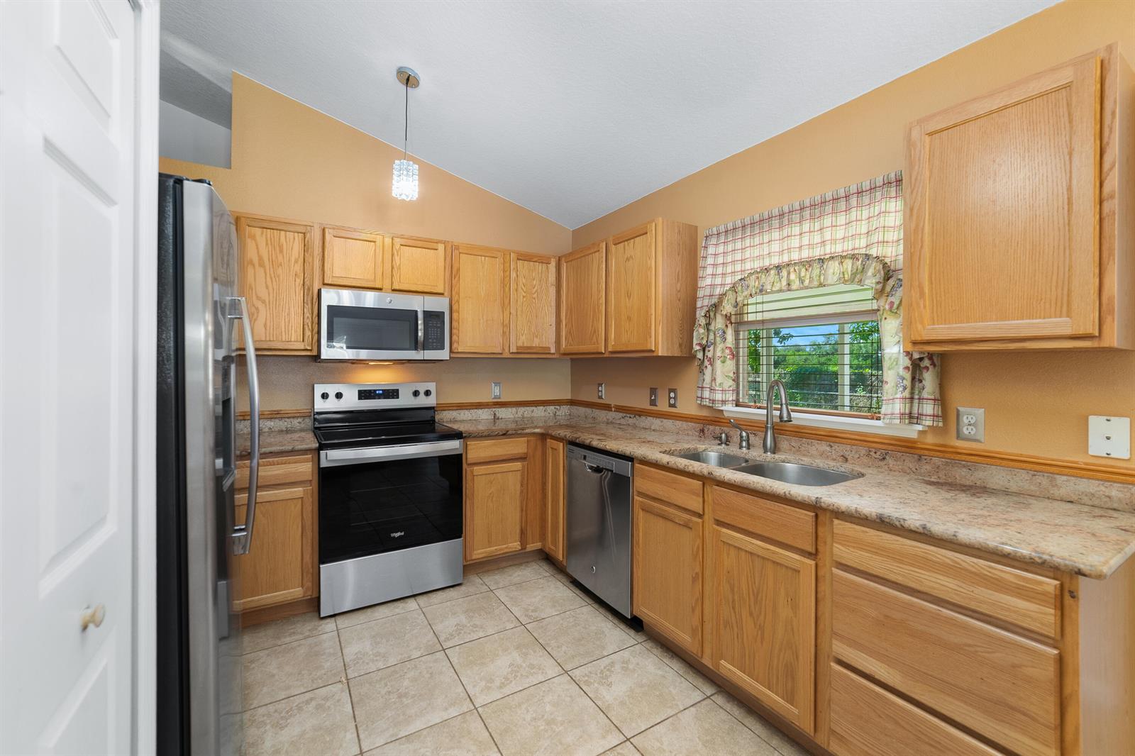 A kitchen with oak cabinets, stainless steel appliances, granite countertops, and tile flooring — 1165 SE 40th Avenue, Okeechobee FL 34974, OKEECHOBEE, FL