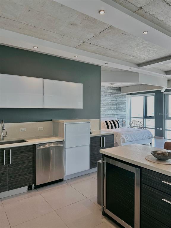 A modern kitchen with dark wood cabinets and stainless steel appliances opens into a bedroom — 404 CONSTITUCION AVE AVENUE UNIT 1706, SAN JUAN, PR