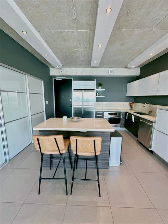 A modern kitchen features a central island, two bar stools, and exposed concrete ceilings — 404 CONSTITUCION AVE AVENUE UNIT 1706, SAN JUAN, PR