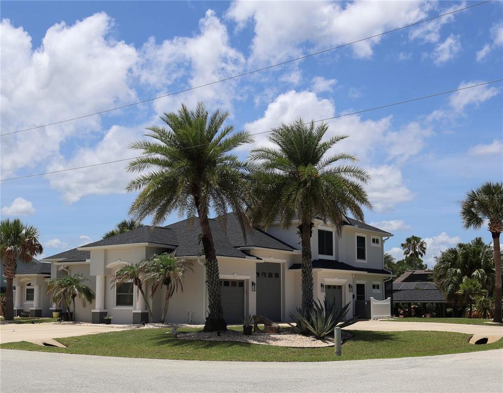 A two-story house with a gray roof, light-colored exterior, and two prominent palm trees — 2 COLONY COURT, PALM COAST, FL