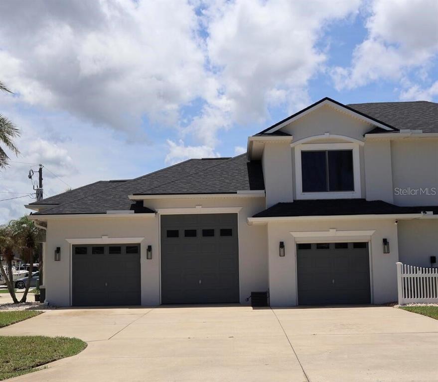 A two-story house features a light-colored exterior, dark roof shingles, and two garage doors — 2 COLONY COURT, PALM COAST, FL