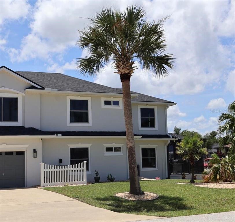 A two-story house with light gray siding, a dark roof, and a palm tree in front — 2 COLONY COURT, PALM COAST, FL