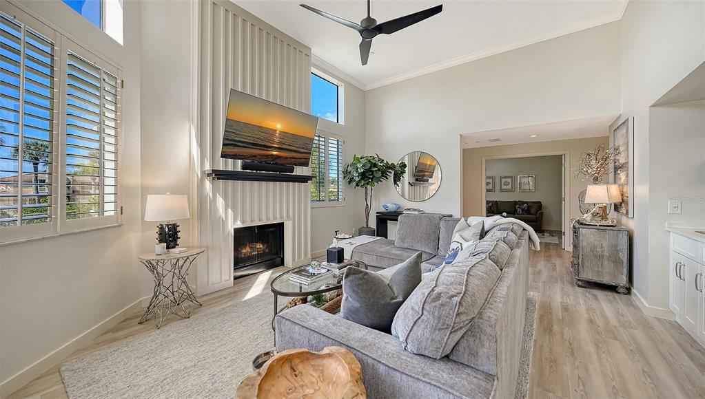 A living room features a fireplace, a gray sectional sofa, and high ceilings — 2000 HARBOURSIDE DRIVE UNIT 1501, LONGBOAT KEY, FL