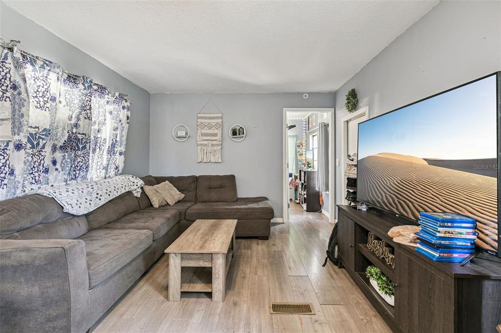 A living room features a gray sectional sofa, a wood coffee table, and a television — 15527 TROUSDALE STREET, CLERMONT, FL