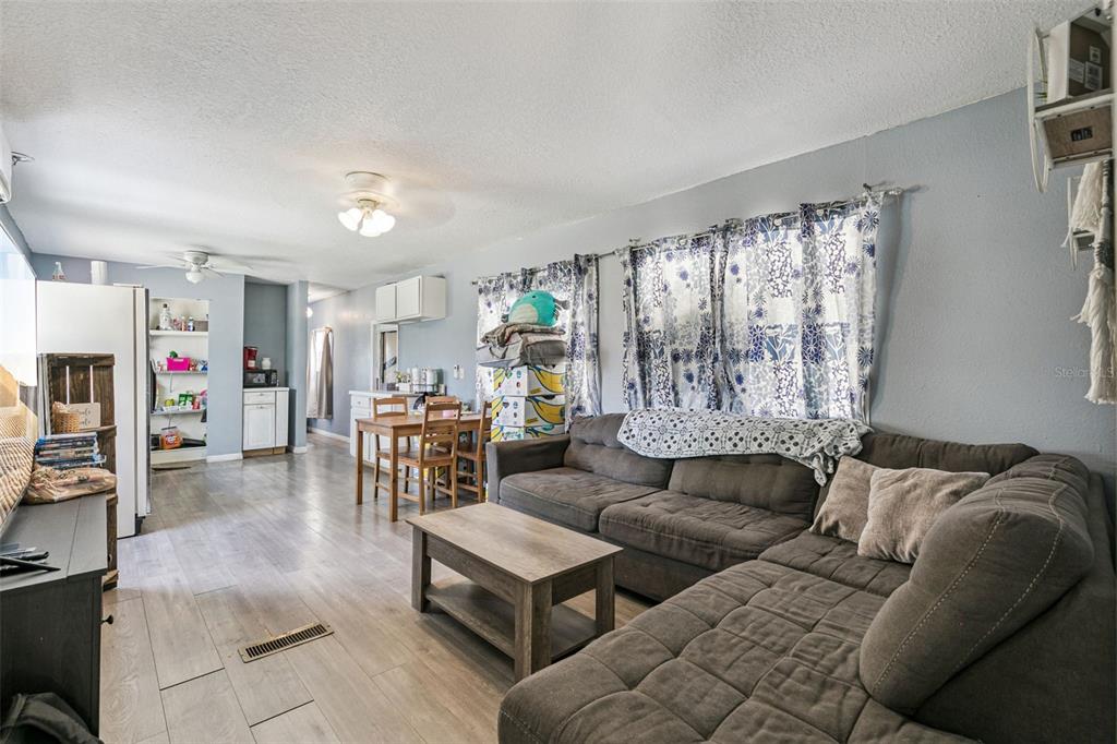 A living room with a sectional sofa, coffee table, dining area, and light wood flooring — 15527 TROUSDALE STREET, CLERMONT, FL