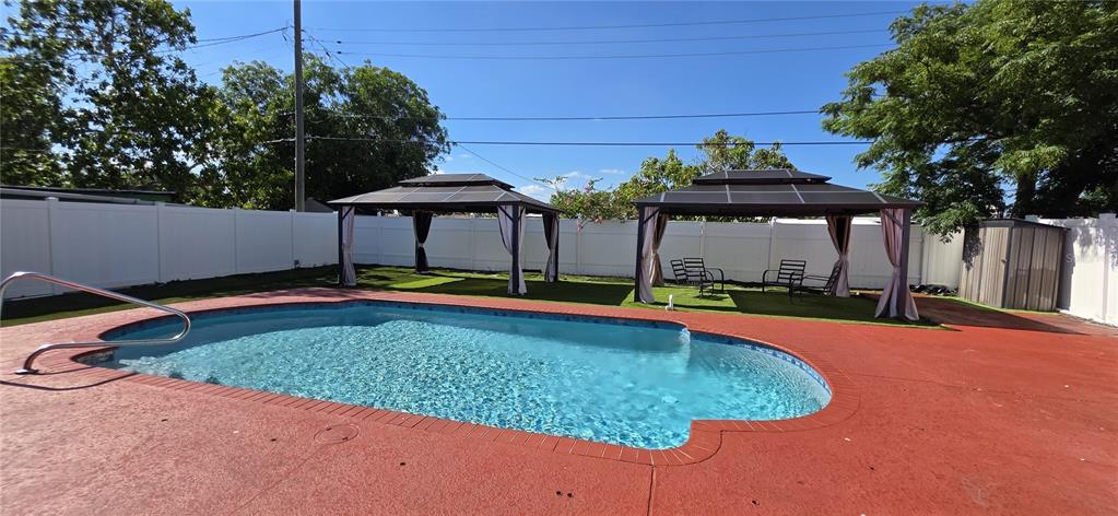 A swimming pool with a red deck and two gazebos sits in a fenced backyard — 6813 TUTTLE STREET, TAMPA, FL