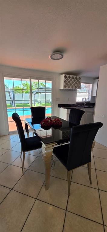 A dining area features a black table with four black chairs and a view of a pool — 6813 TUTTLE STREET, TAMPA, FL