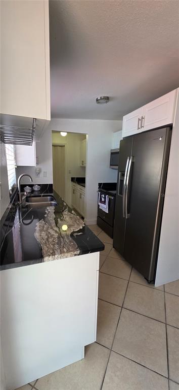A kitchen features white cabinets, dark granite countertops, stainless steel appliances, and tiled flooring — 6813 TUTTLE STREET, TAMPA, FL