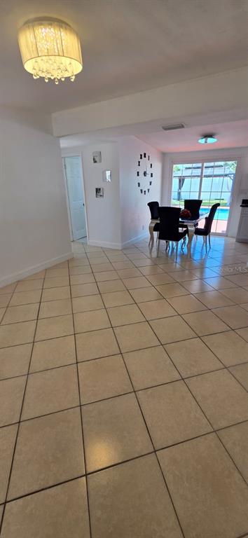 A dining area with tile floors, a crystal chandelier, and a view of a pool — 6813 TUTTLE STREET, TAMPA, FL