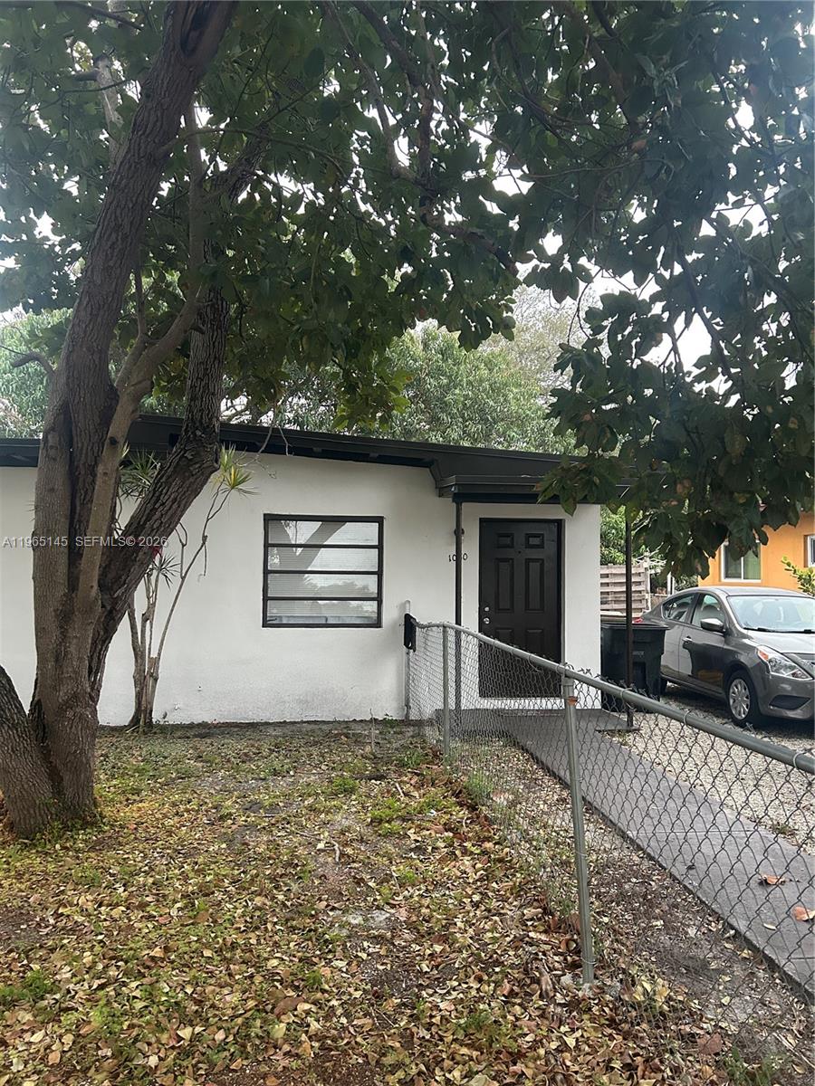 A white single-story house exterior features a dark door, horizontal window, and chain-link fence — 1080 NW 121st St, North Miami FL 33168, NORTH MIAMI, FL