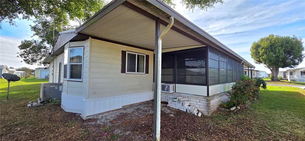 The exterior of a mobile home features a covered carport, a screened porch, and siding — 5650 BENTON STREET, ZEPHYRHILLS, FL