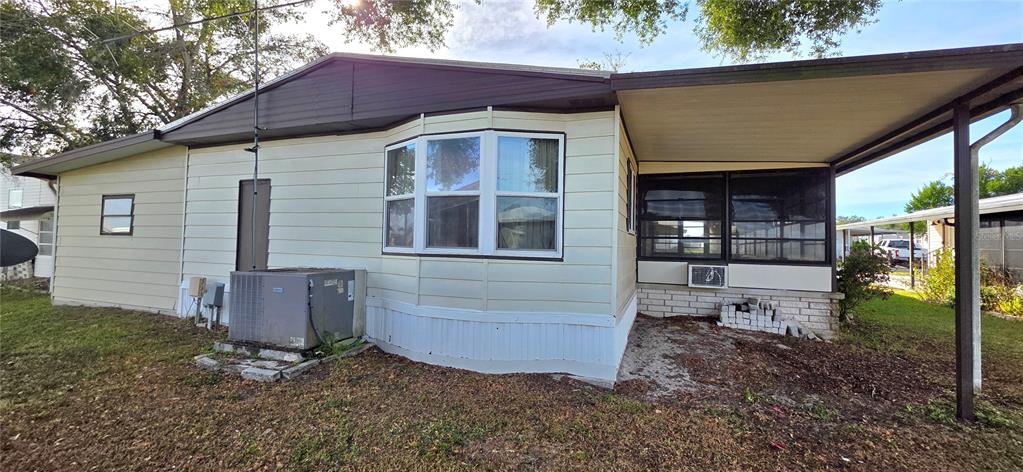 The exterior of a mobile home features a bay window, a screened porch, and siding — 5650 BENTON STREET, ZEPHYRHILLS, FL