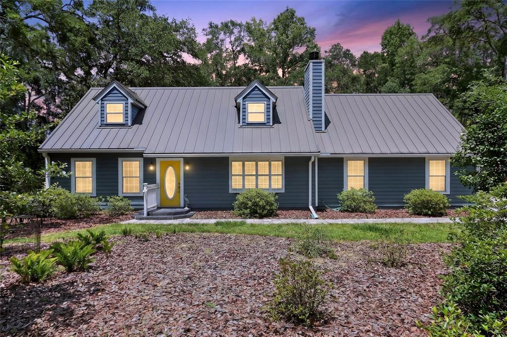 A gray house with a metal roof, dormer windows, and a yellow front door — 5101 NW 65TH LANE, GAINESVILLE, FL