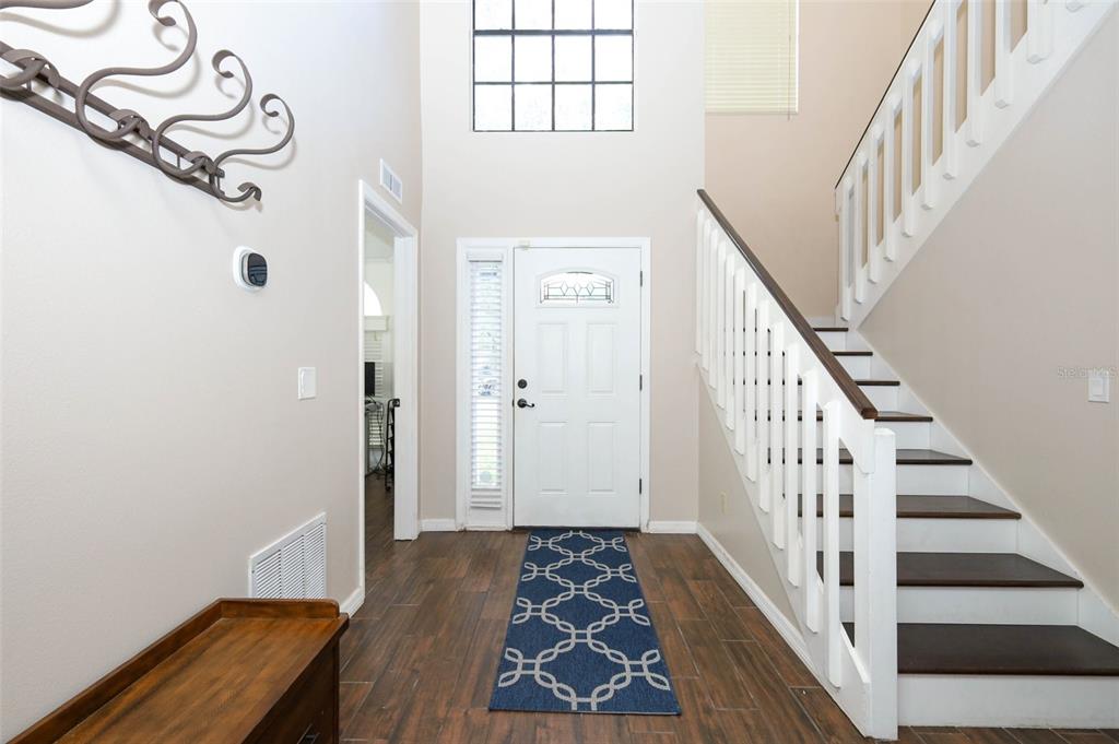 A foyer features wood-look flooring, a white front door, and a staircase with white railings — 1152 TWIN RIVERS BOULEVARD, OVIEDO, FL