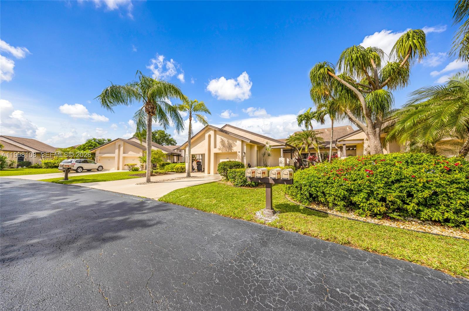 A suburban street view shows single-story houses with driveways, palm trees, and a mailbox cluster — 5302 Fairway Woods Dr # 4612, Delray Beach FL 33484, DELRAY BEACH, FL