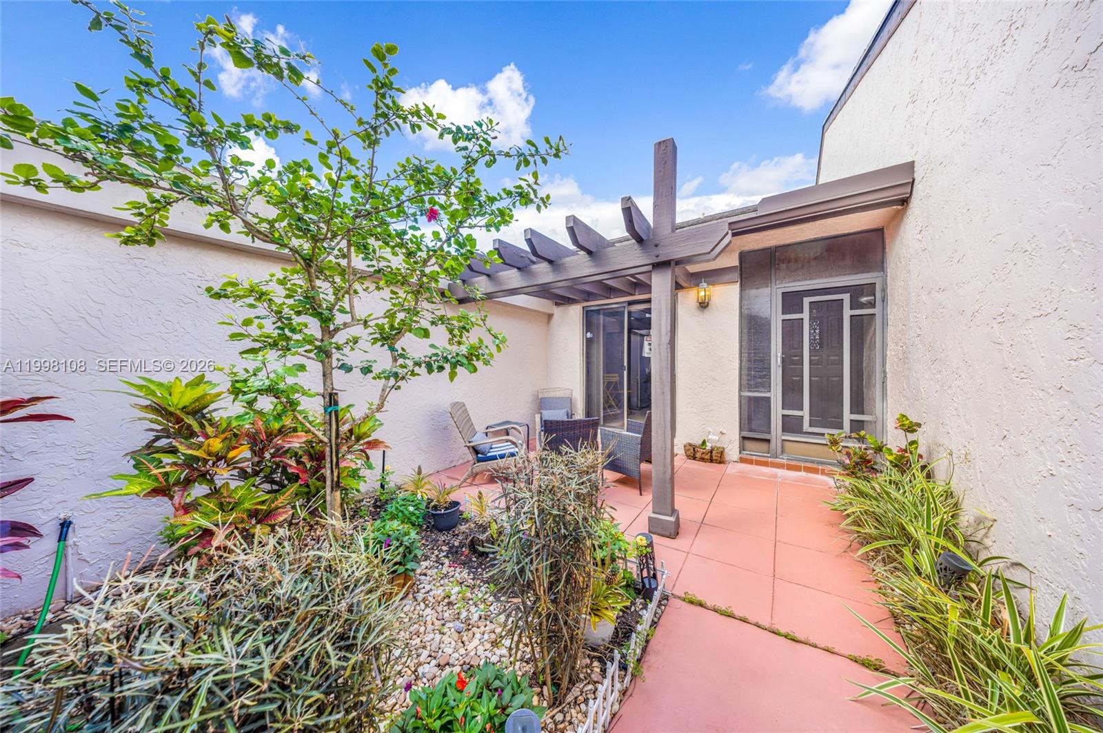 A patio features a wooden pergola, tiled flooring, and a small garden area with plants — 5302 Fairway Woods Dr # 4612, Delray Beach FL 33484, DELRAY BEACH, FL
