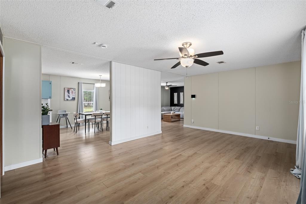 A spacious living room with light wood flooring, a ceiling fan, and an adjacent dining area — 3511 S PALM AVENUE, PALATKA, FL
