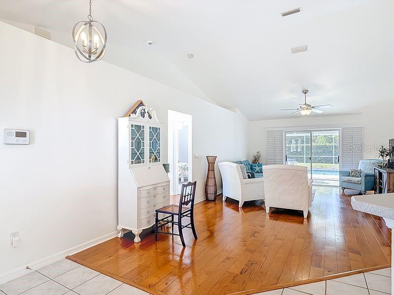 A living room with hardwood floors, a white secretary desk, and a view of a pool — 60 ROLLING SANDS DRIVE, PALM COAST, FL