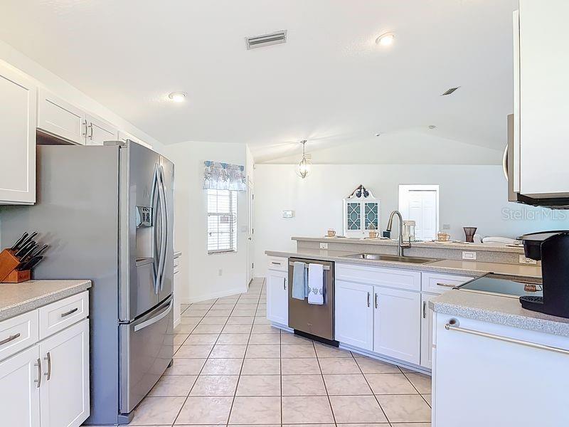 A kitchen with white cabinets, stainless steel appliances, and tile flooring — 60 ROLLING SANDS DRIVE, PALM COAST, FL
