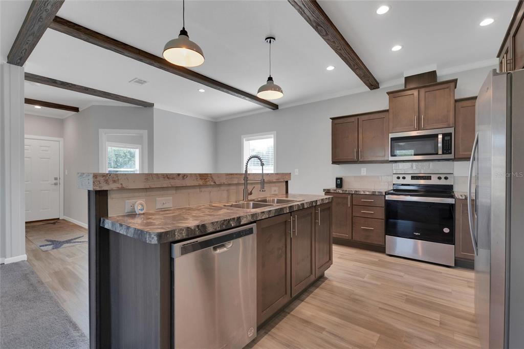 A kitchen features dark wood cabinets, stainless steel appliances, and a raised breakfast bar island — 25294 CANTERBURY DRIVE, LAKE WALES, FL