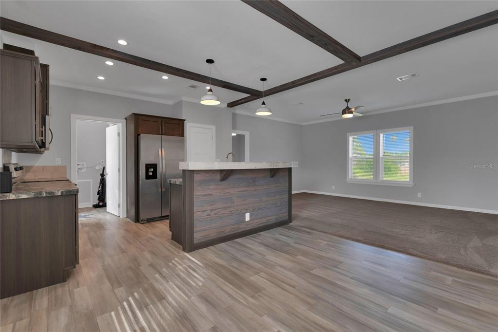 A kitchen with a wood-paneled island and dark cabinets opens into a carpeted living area — 25294 CANTERBURY DRIVE, LAKE WALES, FL