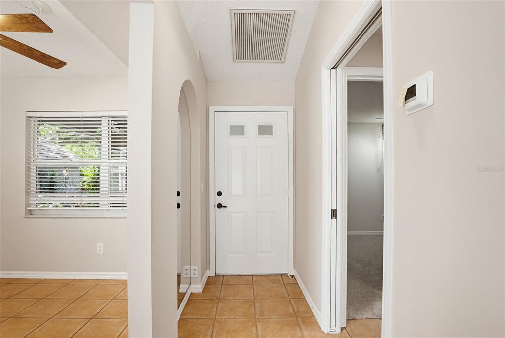 An entryway features a white front door, tiled flooring, and an arched wall opening — 4779 TIVOLI PLACE, SARASOTA, FL