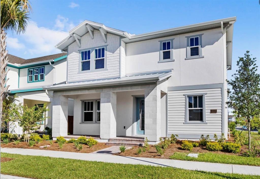 A two-story house with a covered front porch, light-colored siding, and a metal roof — 10133 PEEBLES STREET, ORLANDO, FL