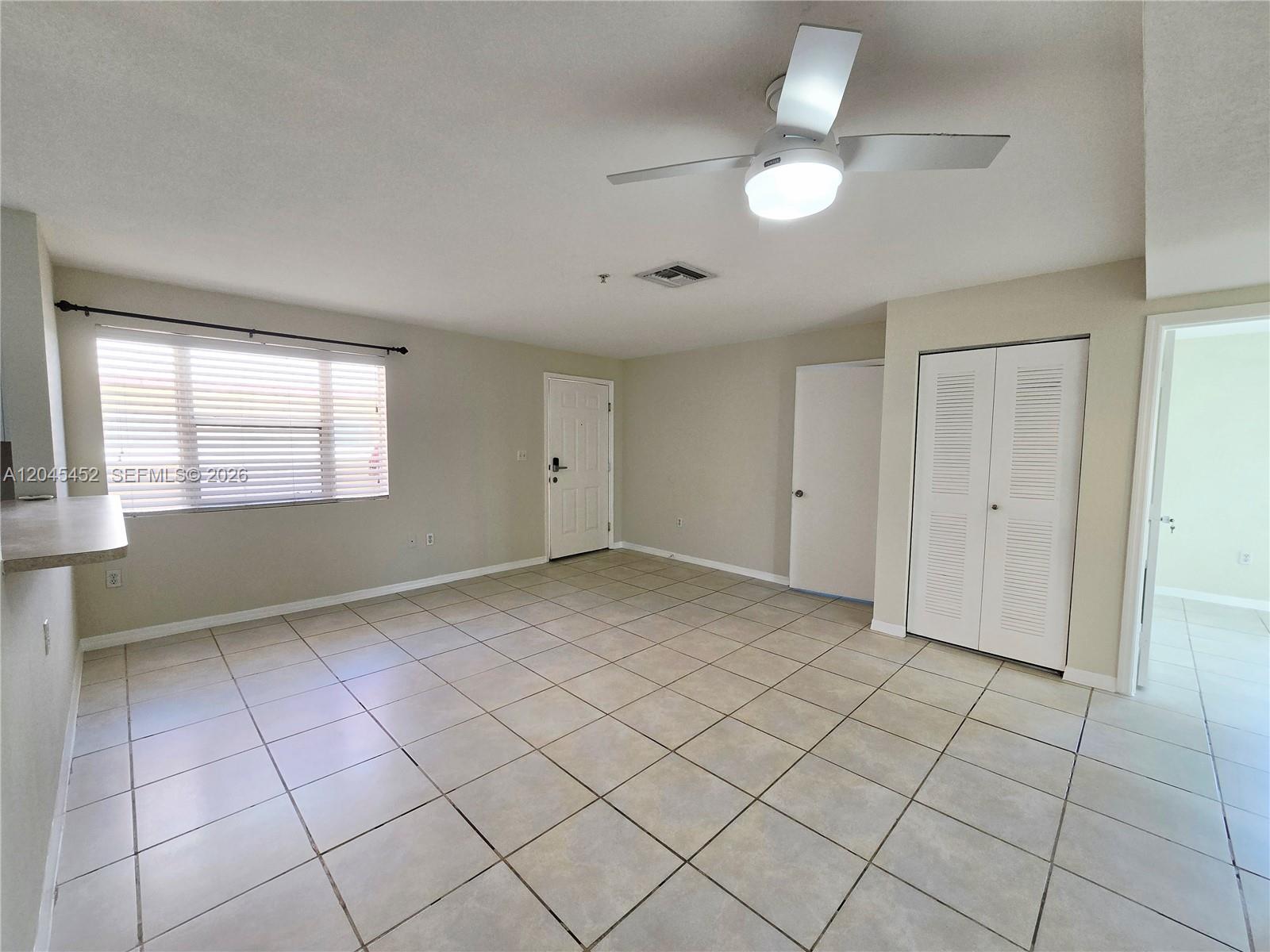 An empty room features beige tile flooring, a ceiling fan, and white louvered closet doors — 1627 NW 18th St # 201, Miami FL 33125, MIAMI, FL