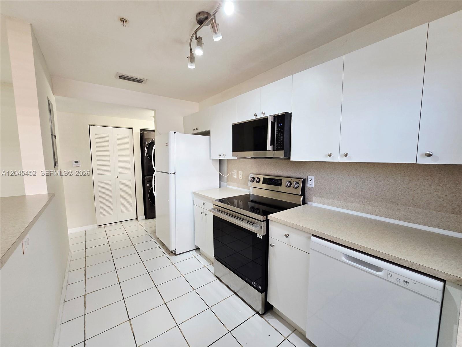 A kitchen features white cabinets, stainless steel appliances, and light-colored tile flooring — 1627 NW 18th St # 201, Miami FL 33125, MIAMI, FL