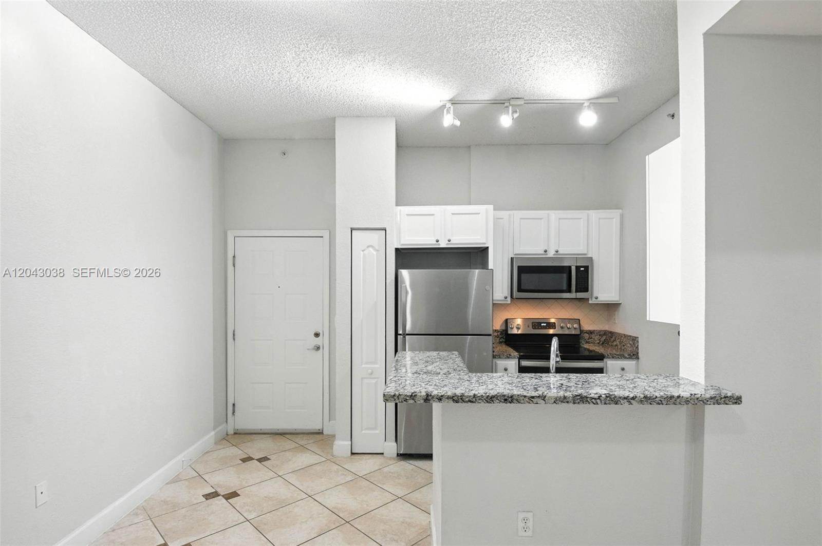 A kitchen features white cabinets, stainless steel appliances, granite countertops, and a tile floor — 6001 SW 70th St # 108, South Miami FL 33143, SOUTH MIAMI, FL