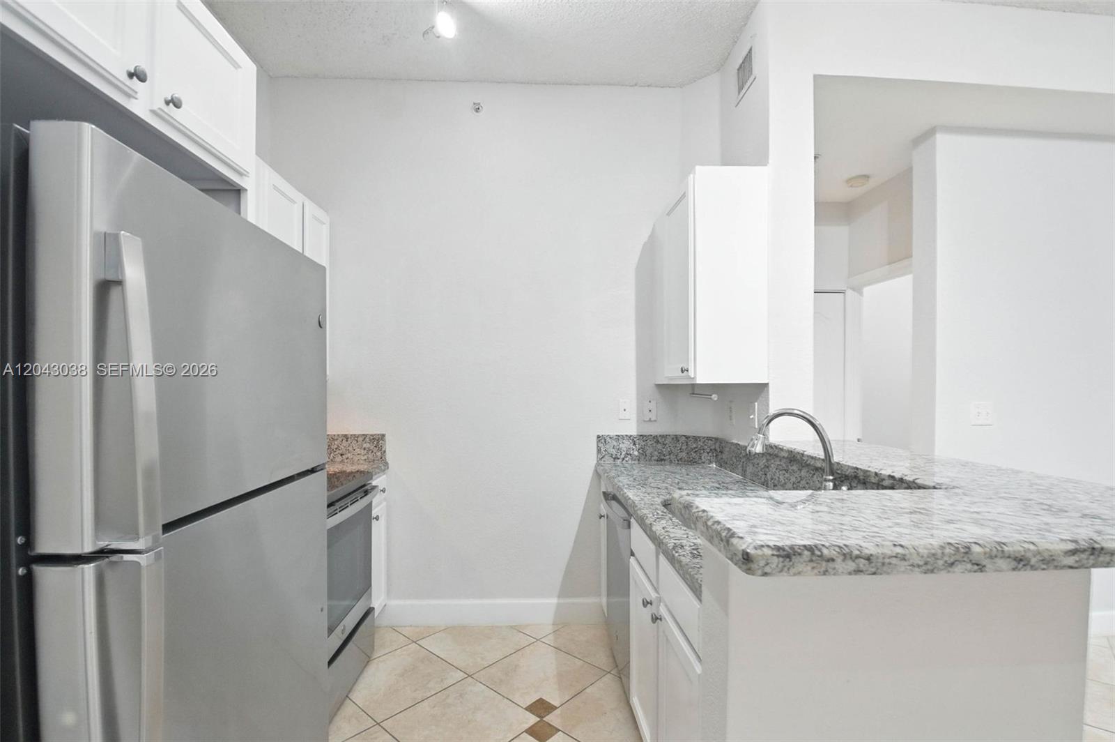 A kitchen features white cabinets, granite countertops, stainless steel appliances, and tile flooring — 6001 SW 70th St # 108, South Miami FL 33143, SOUTH MIAMI, FL