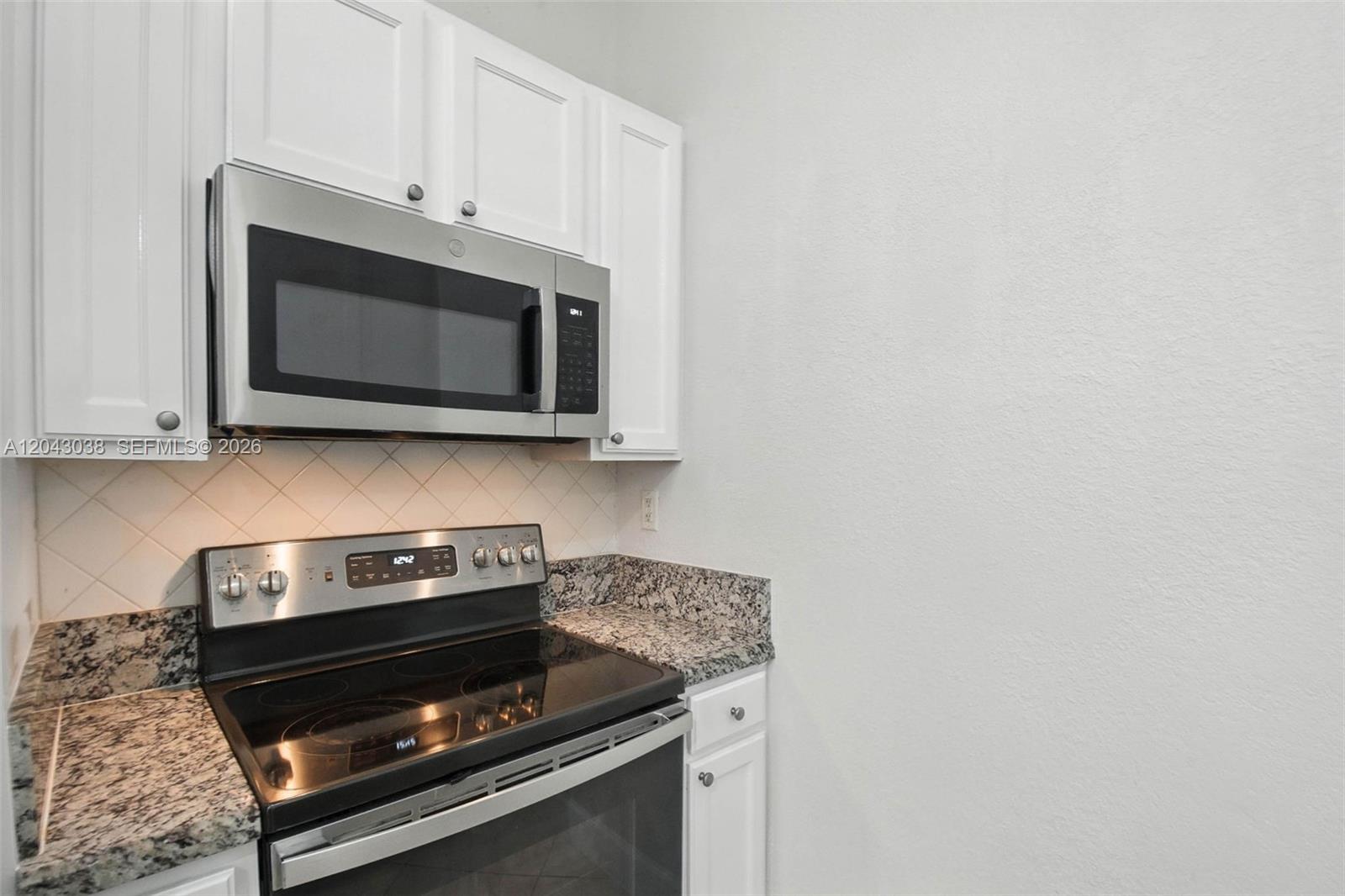 A kitchen features white cabinets, stainless steel appliances, and granite countertops — 6001 SW 70th St # 108, South Miami FL 33143, SOUTH MIAMI, FL