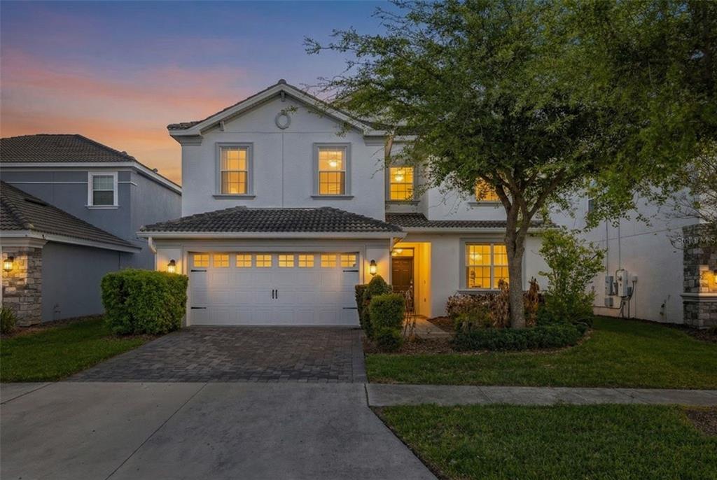 A two-story suburban house with a white stucco facade, tiled roof, and two-car garage — 9044 SAND TRAP DRIVE, DAVENPORT, FL