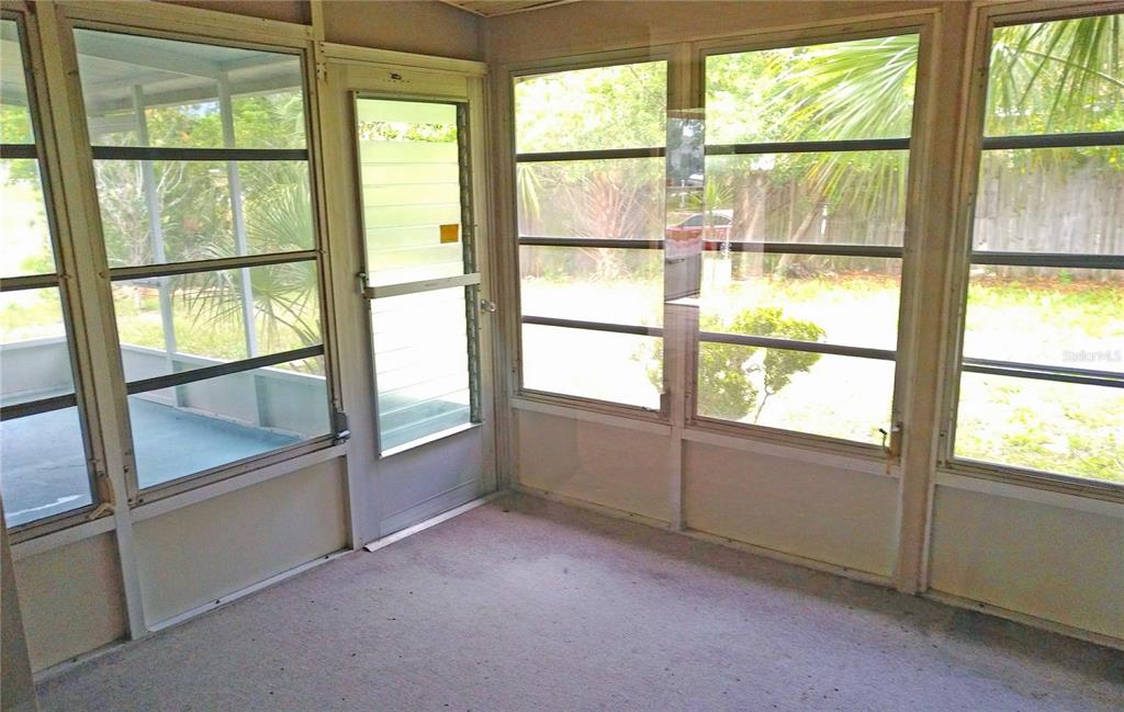 A sunroom features large windows, a screen door, and gray carpeted flooring — 4514 CYNTHIA LANE, SPRING HILL, FL