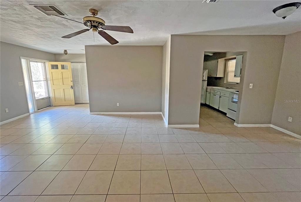 An open-concept living area features light-colored tile flooring, a ceiling fan, and an adjacent kitchen — 4514 CYNTHIA LANE, SPRING HILL, FL