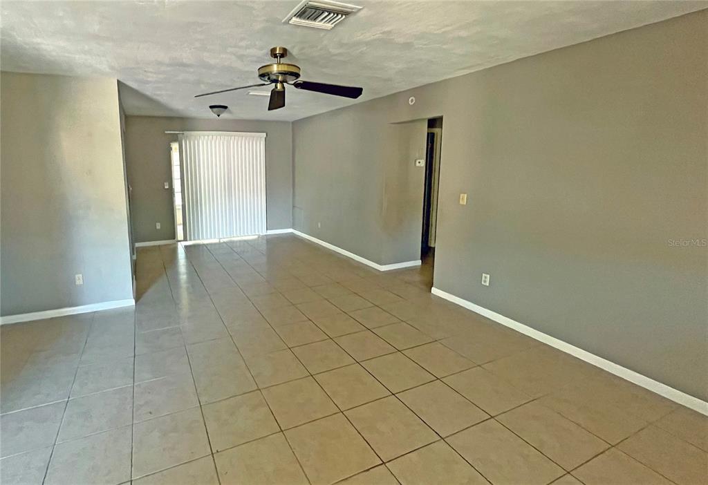 An empty living room features light-colored tile flooring, gray walls, and a ceiling fan — 4514 CYNTHIA LANE, SPRING HILL, FL
