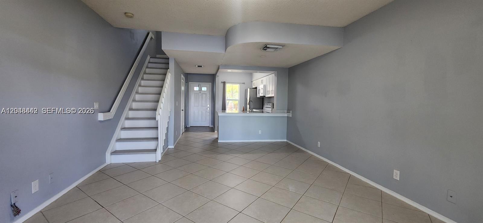 An open living area features tile flooring, a staircase, and a pass-through kitchen window — 211 Mallory Ct, Weston FL 33326, WESTON, FL