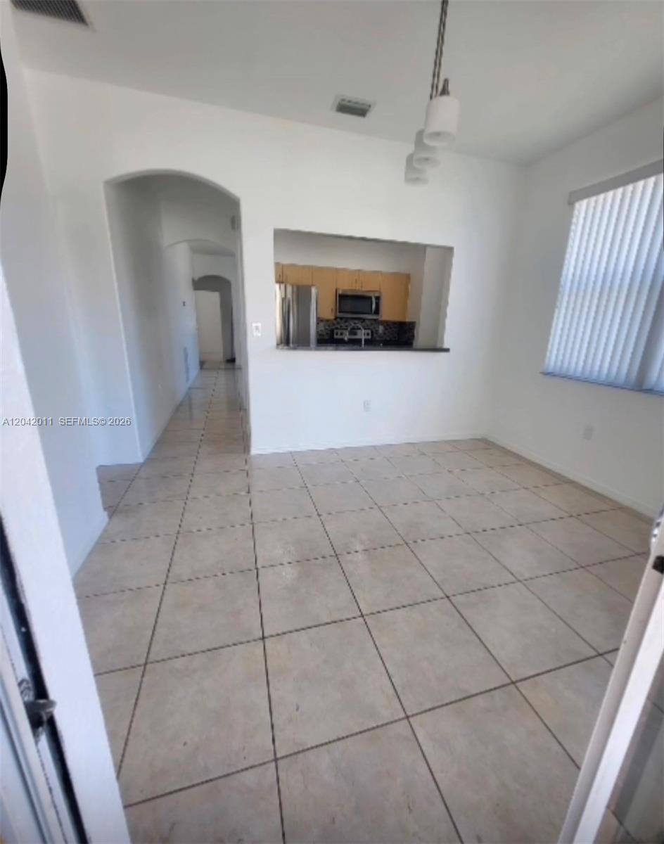 A tiled dining area features a pass-through window looking into a kitchen — 23752 SW 110th Ave, Homestead FL 33032, HOMESTEAD, FL