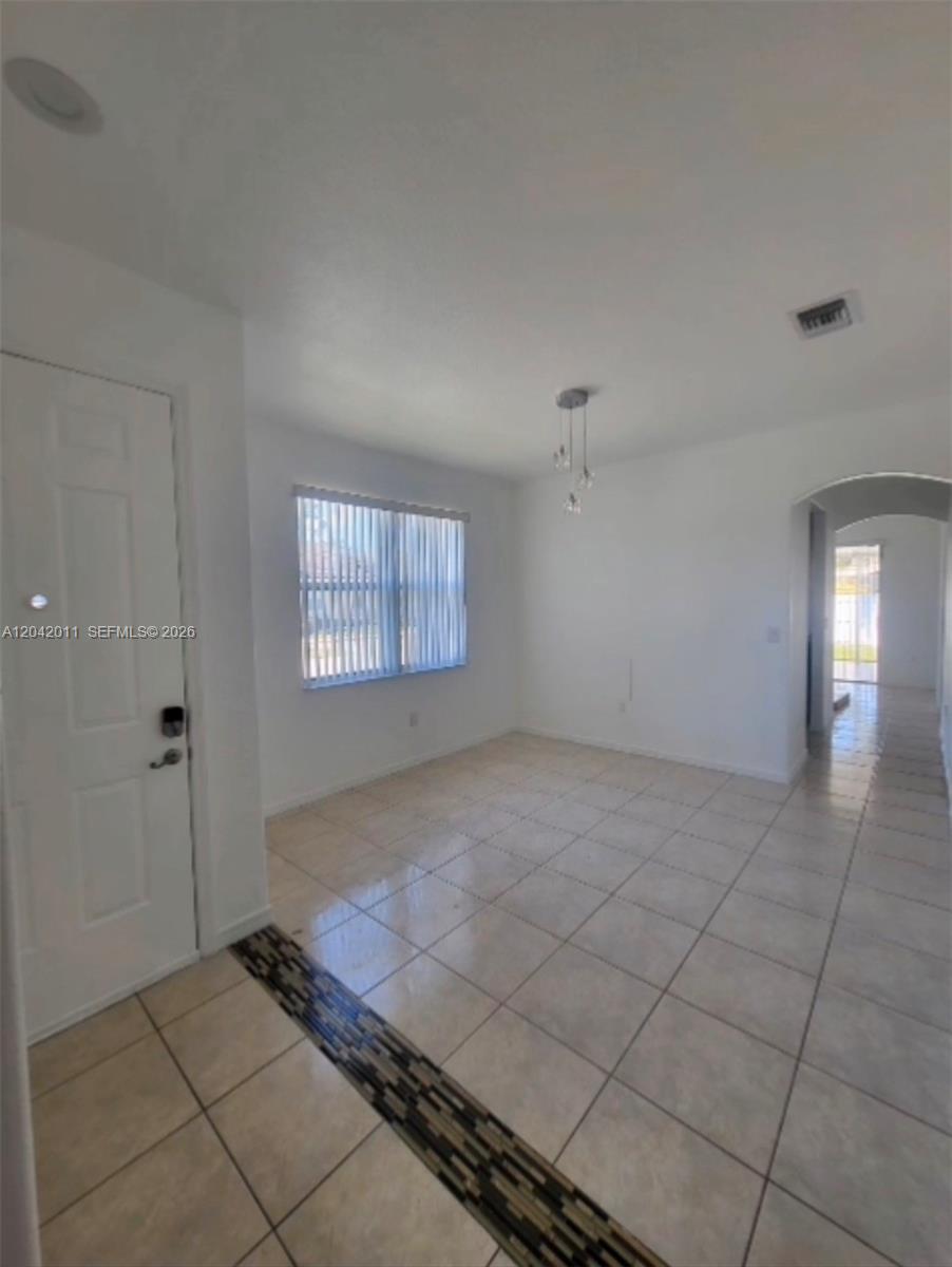 A dining area features white walls, tile flooring, a window with blinds, and a light fixture — 23752 SW 110th Ave, Homestead FL 33032, HOMESTEAD, FL