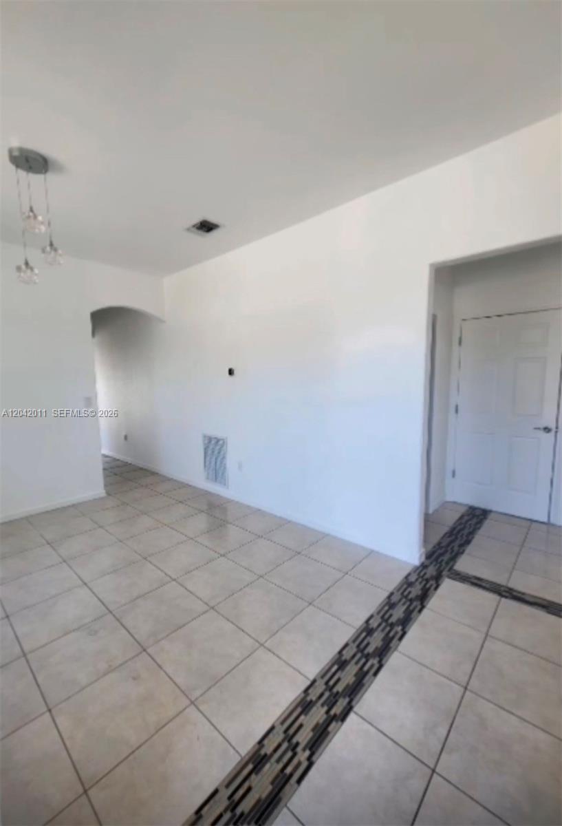 An interior view shows a tiled room with a decorative floor inlay and arched doorway — 23752 SW 110th Ave, Homestead FL 33032, HOMESTEAD, FL