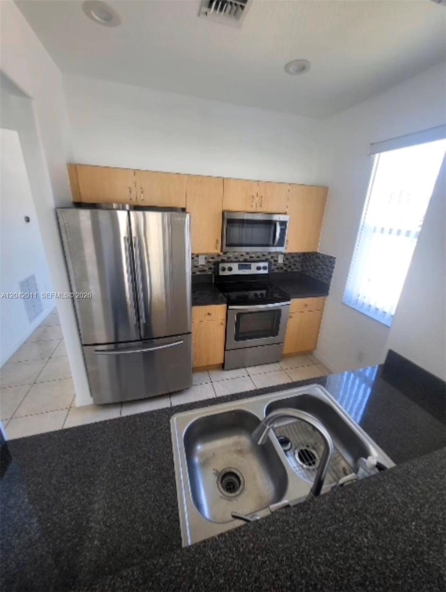 A kitchen features light wood cabinets, stainless steel appliances, and dark granite countertops — 23752 SW 110th Ave, Homestead FL 33032, HOMESTEAD, FL