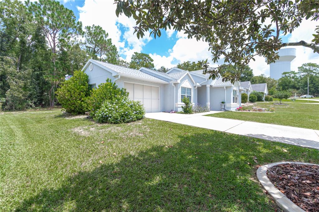 A light-colored single-story house with a garage, driveway, and surrounding lawn under a blue sky — 8795 SW 108TH STREET, OCALA, FL