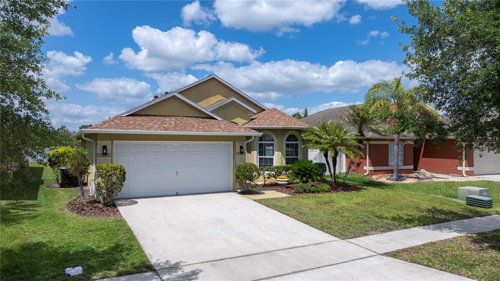 A single-story house with a tan stucco exterior, a two-car garage, and a concrete driveway — 2378 BREWERTON LANE, ORLANDO, FL