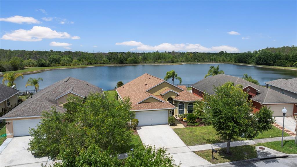 An aerial view shows three suburban houses with garages and driveways facing a large lake — 2378 BREWERTON LANE, ORLANDO, FL