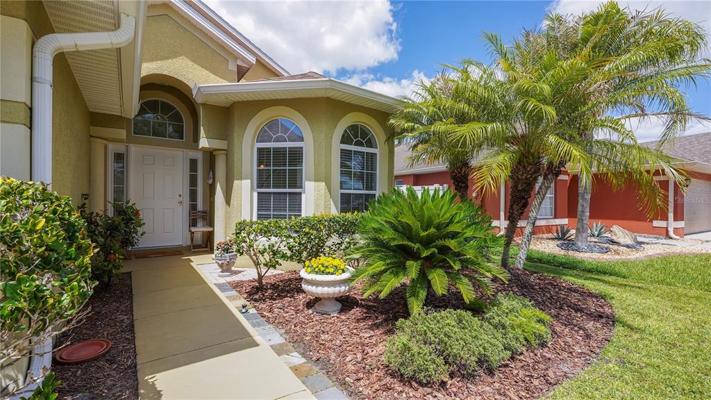 A walkway leads to the front entrance of a house with yellow stucco walls — 2378 BREWERTON LANE, ORLANDO, FL
