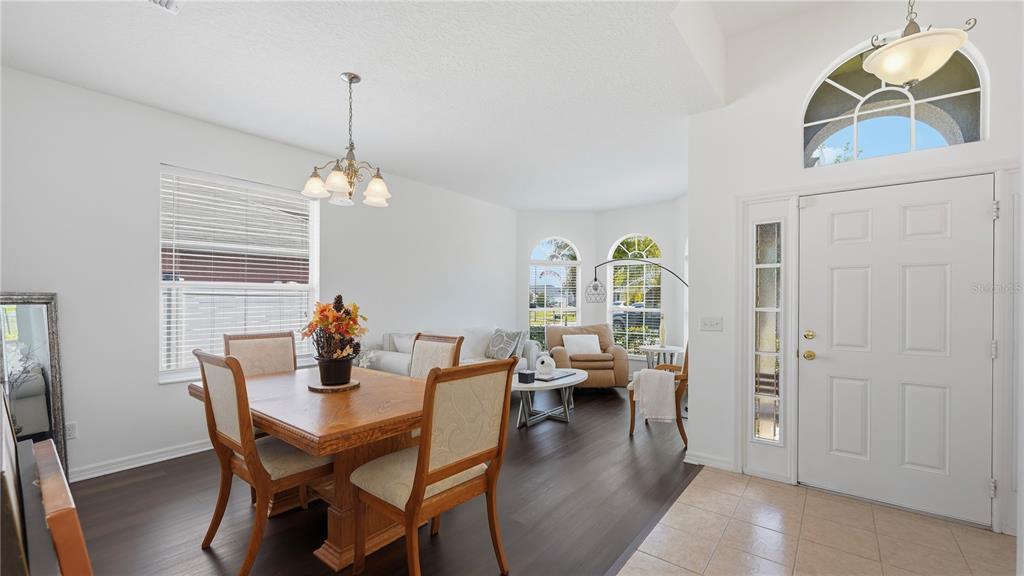 A dining area with a wooden table and chairs sits next to a living room — 2378 BREWERTON LANE, ORLANDO, FL