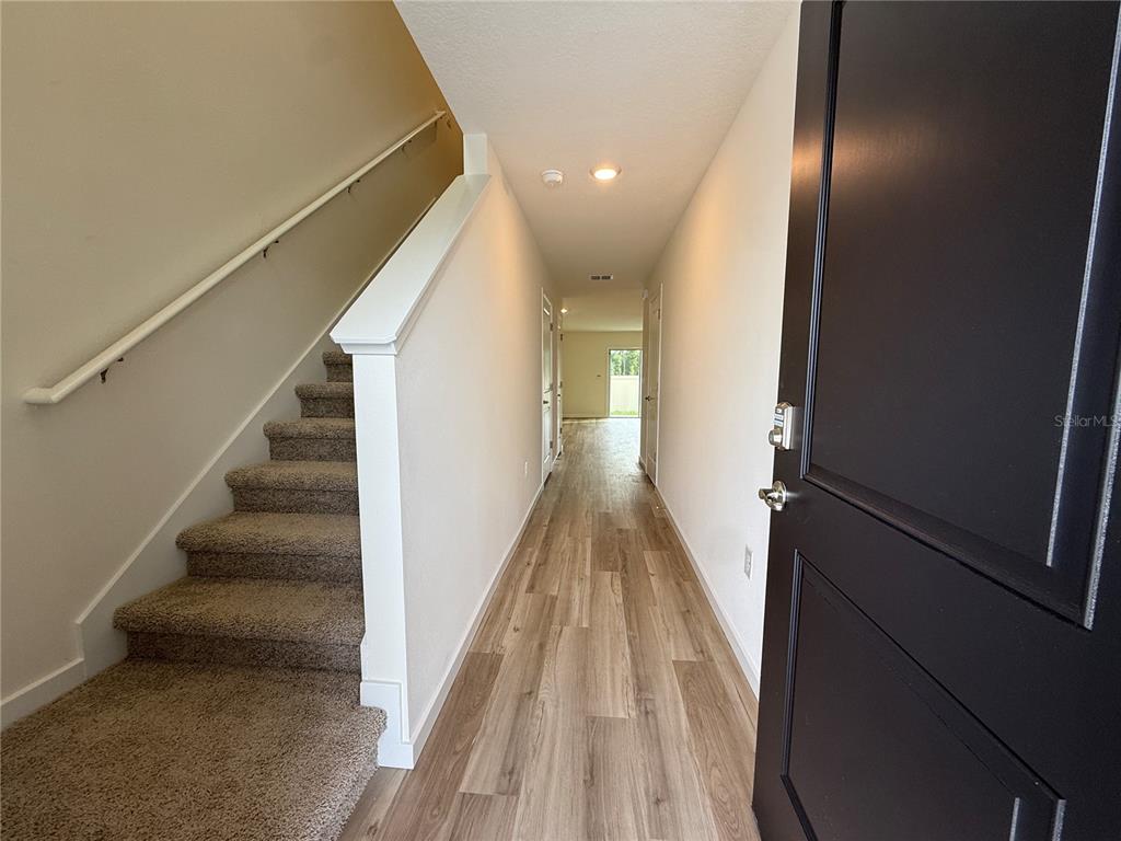 An entryway features a carpeted staircase on the left and wood-look flooring leading to a hallway — 6524 SW 82ND LOOP, OCALA, FL